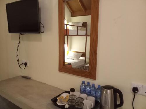 a mirror on a wall next to a table with bottles at Inn On The Bay in Pasikuda