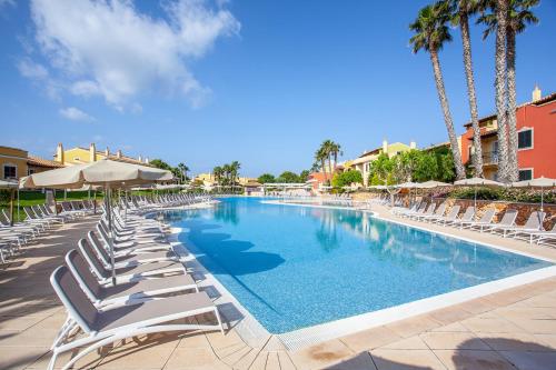 uma piscina com espreguiçadeiras e palmeiras em Grupotel Playa Club em Son Xoriguer