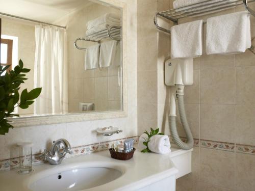 La salle de bains est pourvue d'un lavabo, d'un miroir et d'un téléphone. dans l'établissement Palazzo Vecchio Exclusive Residence, à Réthymnon