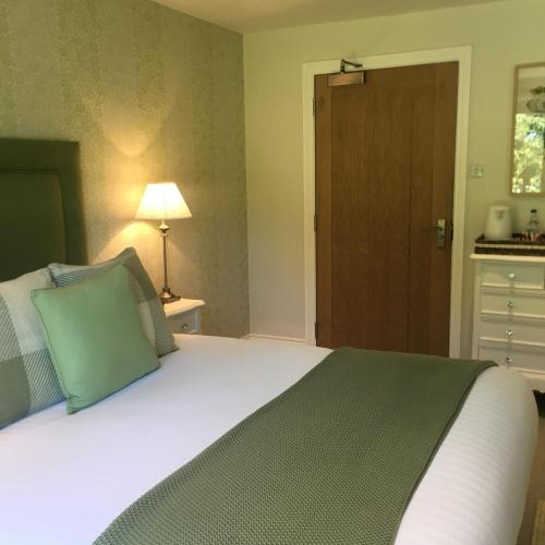 a bedroom with a large bed with a green pillow at The George Great Oxendon in East Farndon