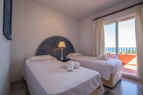 two beds in a room with a view of the ocean at Los Hidalgos Penthouse in Manilva
