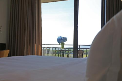 a bedroom with a bed and a table with a vase of flowers at Ambassadori Kachreti Golf Resort in Kachretʼi