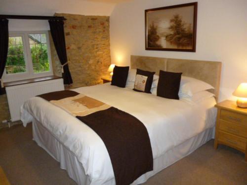 a bedroom with a large white bed with black pillows at Quiet Woman House in Halstock