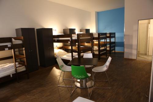 a room with several bunk beds and a table and chairs at Five Elements Hostel Leipzig in Leipzig
