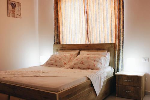a bed with a wooden headboard in a bedroom at Elti Apartment in Sarandë