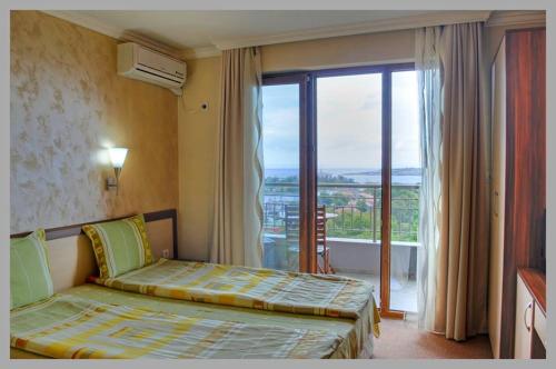 a bedroom with a bed and a large window at Family Hotel Radiana in Sozopol