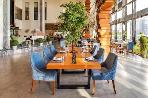 una sala da pranzo con tavolo in legno e sedie blu di Canal Central Hotel Business Bay a Dubai