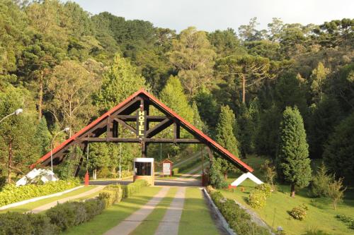 eine Brücke über eine Straße in einem Park mit Bäumen in der Unterkunft Hotel Recanto São Cristóvão - Próximo ao Parque Tarundu in Campos do Jordão