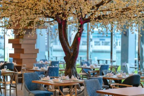 a restaurant with tables and chairs and a tree at Canal Central Hotel Business Bay in Dubai