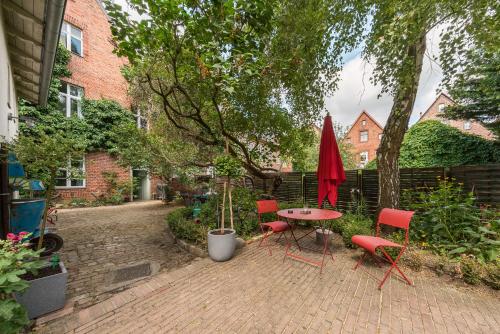 patio ze stołem, krzesłami i czerwonym parasolem w obiekcie Design Apartments - "Im Holländerhaus" w Poczdamie