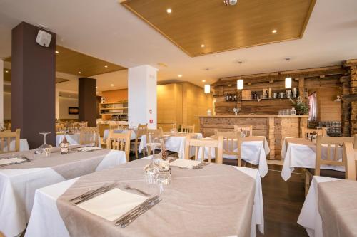 a dining room with white tables and white chairs at Hotel Luna Bianca Folgaria in Folgaria