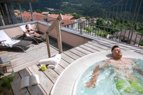 Ein Mann in einem Whirlpool auf einem Balkon in der Unterkunft Hotel Luna Bianca Folgaria in Folgaria