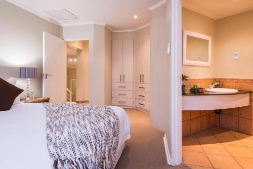 a bedroom with a bed and a bathroom with a sink at aha Kopanong Hotel & Conference Centre in Bredell