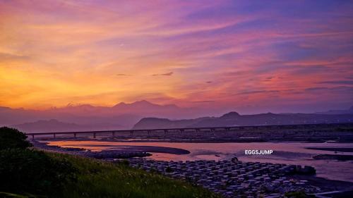 a sunset over a river with a bridge at 台東愛格斯 單車友善&溯溪&包車旅行 EGGS Bike & River tracing & Chartered car tour in Taitung City