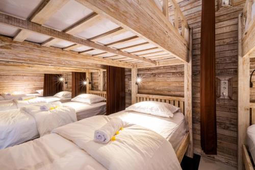 four beds in a room with wooden walls at Nyuh Gading Home Stay in Nusa Lembongan