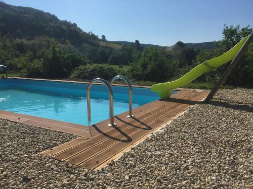 a slide next to a swimming pool with a playground at Alcove Du Velay in Rochelimagne