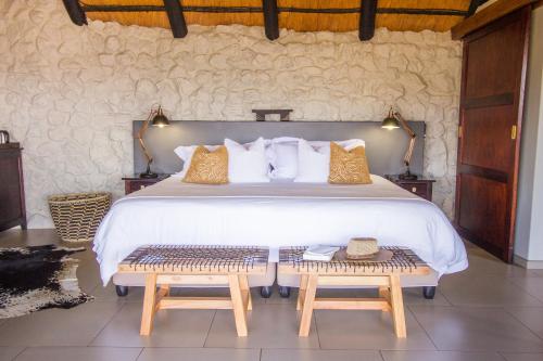 - une chambre avec un grand lit et 2 bancs dans l'établissement Leopard Mountain Safari Lodge, à Manyoni Private Game Reserve