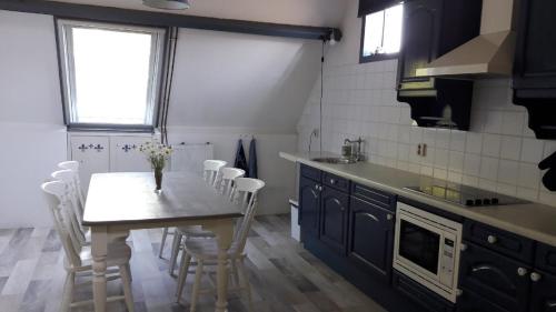 a kitchen with a table with white chairs and a sink at Noord-Hollands Hof Dream in Spijkerboor