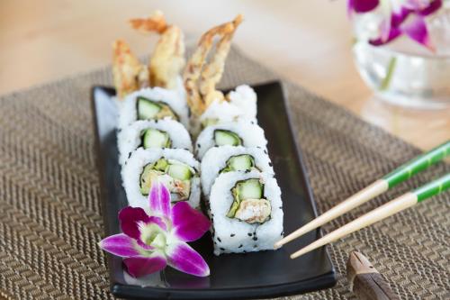 a plate of sushi and a purple flower on a table at Ascott Palace Dhaka in Dhaka