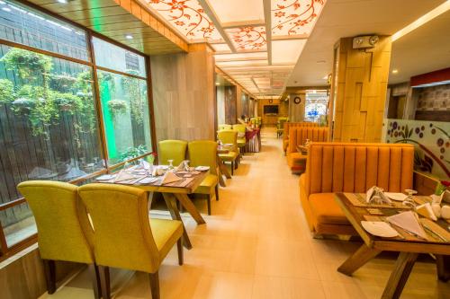 a restaurant with wooden tables and yellow chairs at Ascott Palace Dhaka in Dhaka