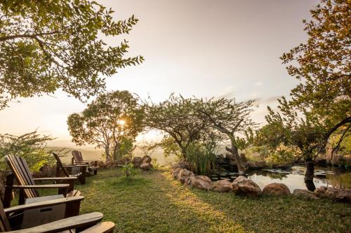 a backyard with a pond and chairs and trees at Leopard Mountain Safari Lodge in Manyoni Private Game Reserve