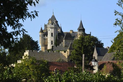 a castle on a hill with trees at La Barde Montfort, votre maison d'hôtes à 4 kms de Sarlat Dordogne in Vitrac
