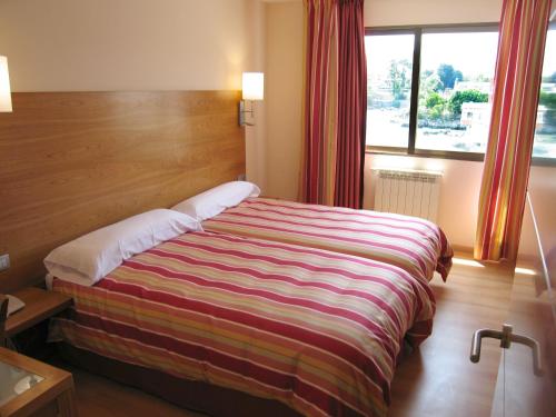 a bed in a hotel room with a large window at Apartamentos Astuy in Isla
