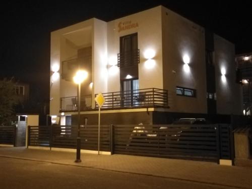 a building with lights on the side of it at night at Pokoje Sandra I in Łeba