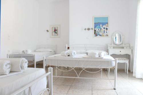 a white room with two beds and a mirror at Katerina Yalos in Ios Chora