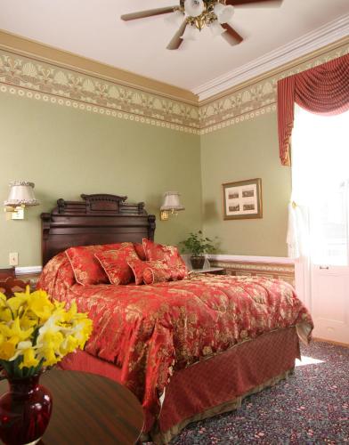 a bedroom with a bed with a red comforter at The Queen Victoria in Cape May
