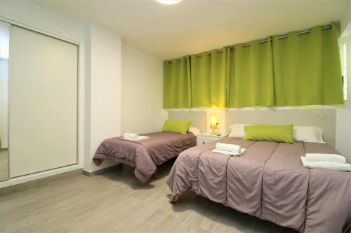 ベニドルムにあるAgua Azul 4-A Apartment Levante-Rincon de Loixの緑のカーテンが備わる客室のベッド2台