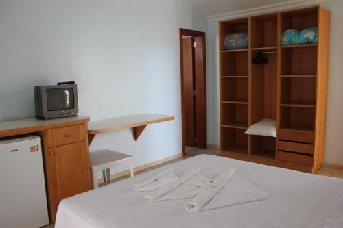 a room with a bed with a tv and a closet at Pousada Lugar ao Sol in Bombinhas