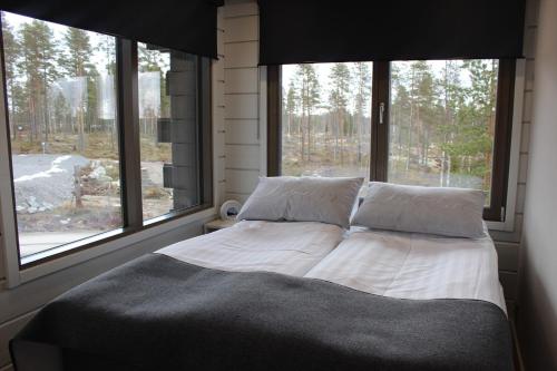 a bed in a bedroom with two large windows at Naava Chalet Pikku Panda (305) in Ähtäri