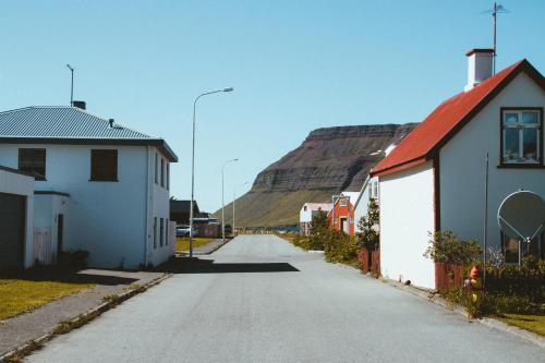 an empty street with a mountain in the background at Fisherman Guesthouse Sudureyri in Suðureyri