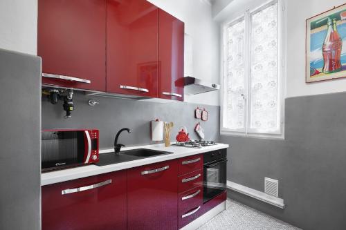 uma cozinha com armários vermelhos e um lavatório em Silver Sword Suite em Florença