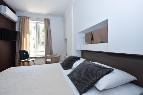 Un dormitorio con una cama blanca y una ventana. en Rooms Patricija, en Zadar