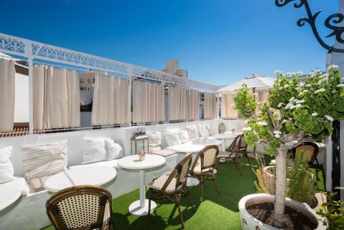 a patio with white tables and chairs and a tree at The Town House - Adults Only in Marbella