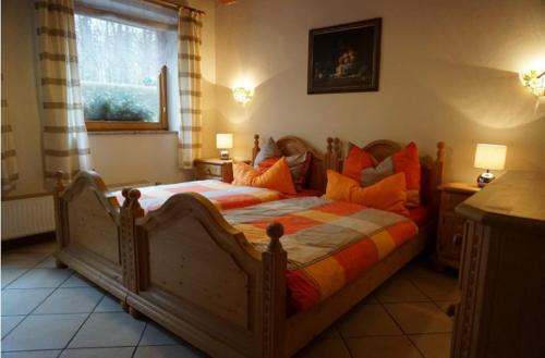 a bedroom with a large wooden bed with orange pillows at Ferienwohnung Näfelt in Gunzenhausen