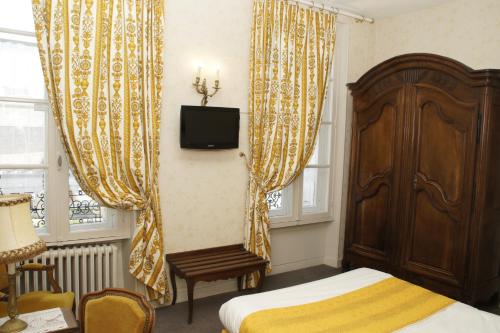- une chambre avec un lit, une télévision et des rideaux dans l'établissement Hotel Montsegur, à Carcassonne