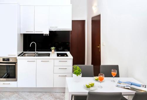 a kitchen with white cabinets and a table with glasses of wine at Apartmani Lučica in Mimice