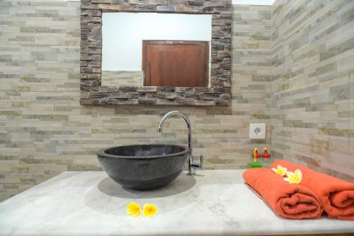 a bathroom with a black sink with orange towels and a mirror at Ina Inn in Ubud