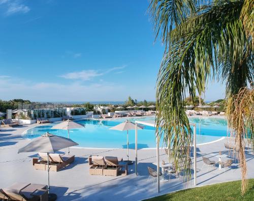 a large swimming pool with chairs and umbrellas at VOI Marsa Siclà Essentia in Sampieri