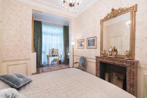 - une chambre avec un lit, un miroir et une cheminée dans l'établissement Veeve - Antique Charm by Arc de Triomphe, à Paris