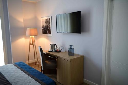 a bedroom with a desk with a television on a wall at 50 SUITE Guesthouse in Naples