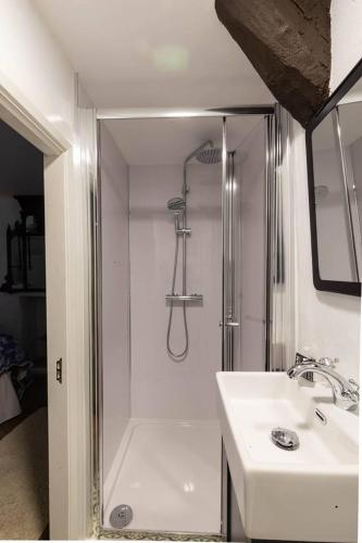 a white bathroom with a shower and a sink at Cissy's Cottage - traditional thatched cottage, on the Causeway Coast in Aghanloo