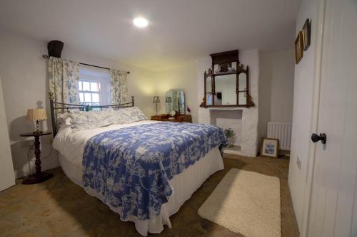 1 dormitorio con 1 cama con manta azul y ventana en Cissy's Cottage, en Aghanloo