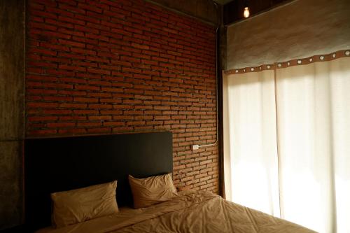 a bedroom with a brick wall and a bed at Black Elephant Boutique in Surat Thani