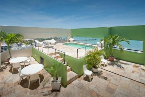 a balcony with tables and chairs and a swimming pool at Iracema Travel in Fortaleza