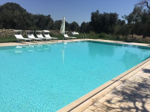 una gran piscina azul con sillas y árboles en agricampeggio GLAMPING MARCONI, en Veglie