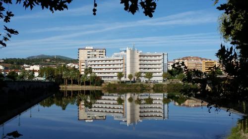a city skyline with a reflection in a body of water at Grande Hotel Dom Dinis in Mirandela